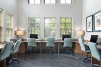 Bright and spacious office space with multiple workstations, large windows, and modern chairs.