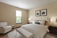 Sophisticated bedroom with a plush queen-sized bed, accent chair, and tasteful decor.