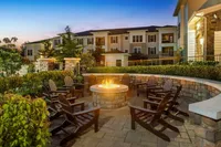 Inviting outdoor seating area with a warm fire pit surrounded by lush greenery at sunset.