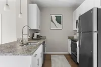 Sleek kitchen design with granite countertops, stainless steel appliances, and white cabinetry.