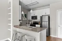 Modern kitchen with granite countertops, stainless steel appliances, and pendant lighting.