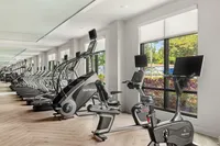 Modern gym with advanced exercise machines and large windows.