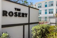 Entrance to The Rosery with modern apartments in the background and lush greenery.