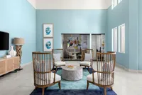 Modern lounge with stylish wooden chairs, artistic decor, and a calming blue palette.
