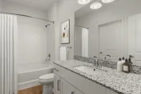 Contemporary bathroom with granite countertop, white cabinetry, and tiled shower.