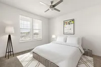 Bright bedroom with modern decor, featuring a comfortable bed, stylish lamp, and elegant artwork.