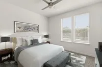Elegant bedroom featuring a plush bed, contemporary artwork, and two large windows with ample natural light.