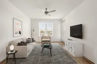 Bright and welcoming living room with modern furniture, large windows, and a stylish ceiling fan.