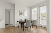 Contemporary dining space with a wooden table, four chairs, and large windows providing natural light.