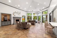 Inviting modern lounge area with elegant furnishings, cozy fireplace, and abundant natural light from large windows overlooking lush greenery.