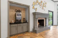Inviting apartment space featuring a cozy fireplace, elegant gray cabinetry, and a convenient coffee station.