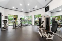 Modern fitness center with large windows, featuring cardio machines and weightlifting equipment in a bright, airy space.
