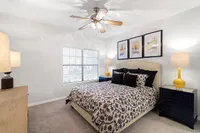 Elegant bedroom showcasing a plush bed with patterned bedding, cozy lighting, and artistic wall decor.