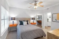 Inviting bedroom with elegant decor, featuring a plush bed, stylish side tables with chic lamps, and a view into a cozy living area.