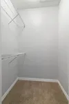 Spacious walk-in closet with sleek white shelving and plush carpet flooring, perfect for organized living.
