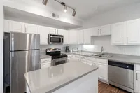 Modern kitchen with sleek stainless steel appliances, pristine white cabinetry, and elegant countertops.