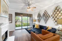 Elegant living room with chic decor, featuring a plush navy sofa, stylish metal wall art, and a large sliding glass door leading to a lush outdoor view.