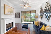 Chic living room with elegant decor, cozy fireplace, and large sliding doors opening to a lush garden view, inviting natural light.