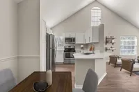 Modern open-concept kitchen and dining area with sleek stainless steel appliances, elegant white cabinetry, and a cozy living space featuring natural light.