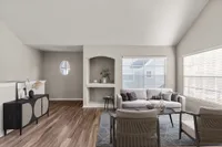 Elegant living room with modern decor, featuring a plush sofa, stylish armchairs, and abundant natural light from large windows.