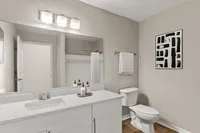 Modern bathroom with sleek white vanity, elegant light fixtures, and contemporary wall art.