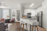 Modern open-concept living space featuring a sleek kitchen with stainless steel appliances, cozy seating area, and elegant bar stools.