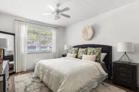 Bright, inviting bedroom with a plush bed, elegant decor, and abundant natural light through a large window.