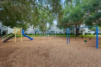 Charming playground with vibrant slides and swings, nestled under lush trees in a serene residential community.