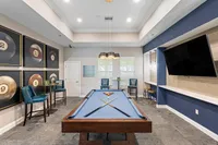 Chic recreation room featuring a stylish pool table, modern artwork, and a comfortable seating area, perfect for entertainment and relaxation.