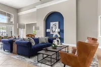 Elegant living room with plush blue sofas and leather chairs, accented by sophisticated decor and ample natural light.