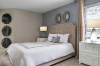 Elegant bedroom with plush upholstered bed, chic wall art, and stylish bedside tables illuminated by soft lamps.