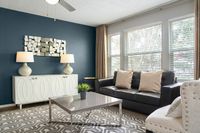Bright and inviting living room featuring modern decor, a sleek black sofa, and elegant lighting against a rich accent wall.