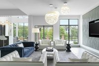 Modern clubhouse with elegant seating, statement lighting, and expansive windows showcasing a garden view.