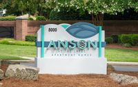Charming Anson at the Lakes apartment homes entrance sign surrounded by lush greenery and natural stone accents.