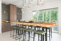 Contemporary kitchen with stylish wooden countertop, sleek pendant lighting, and lush views through expansive windows.