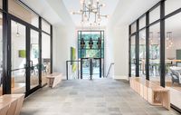 Elegant apartment lobby showcasing modern glass doors, chic lighting fixtures, and a view of a serene outdoor pool area.
