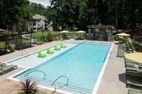 Luxurious apartment pool area featuring modern green loungers, poolside cabanas, and lush greenery for a relaxing escape.