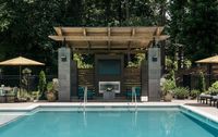 Luxurious outdoor pool area featuring a stylish cabana with comfortable seating, surrounded by lush greenery and umbrellas, perfect for relaxation and entertainment.