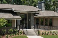 Modern home exterior with sleek stone facade and inviting entrance surrounded by lush greenery.