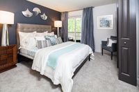 Inviting bedroom with elegant decor featuring a plush bed, stylish cushions, and contemporary art; brightened by natural light from large windows and complemented by modern lighting fixtures.