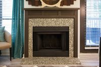 Charming living space with a beautifully designed granite fireplace, surrounded by elegant decor and serene teal curtains.