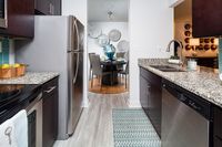 Modern kitchen with sleek stainless steel appliances and elegant granite countertops, leading to a stylishly decorated dining area with unique wall art.
