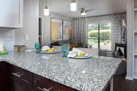 Contemporary apartment with elegant granite countertop, stylish dining setup, and cozy living area featuring chic decor and large windows offering garden views.