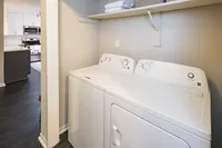 Chic apartment laundry area featuring modern washer and dryer with adjacent stylish kitchen visible.
