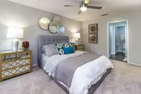 Elegant bedroom featuring a plush gray headboard, artistic wall decor, and stylish mirrored nightstands with ambient lighting.