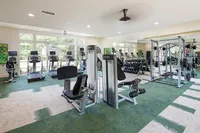 Bright and inviting fitness center with modern exercise equipment, featuring treadmills, weight machines, and a mirrored wall for a sleek, open feel.