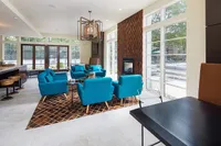 Modern living area with vibrant blue seating, stylish wooden accents, and a cozy fireplace, overlooking a scenic patio.