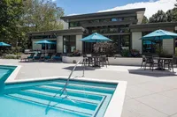 Luxurious modern patio featuring a sparkling swimming pool, stylish lounge chairs, and vibrant umbrellas, perfect for relaxation and entertaining.