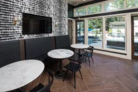 Chic lounge area with elegant marble-top tables, modern chairs, and a vibrant pool view through large windows, perfect for relaxation.