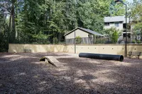 Inviting outdoor dog park with agility equipment set amidst lush greenery, perfect for pet-friendly living.